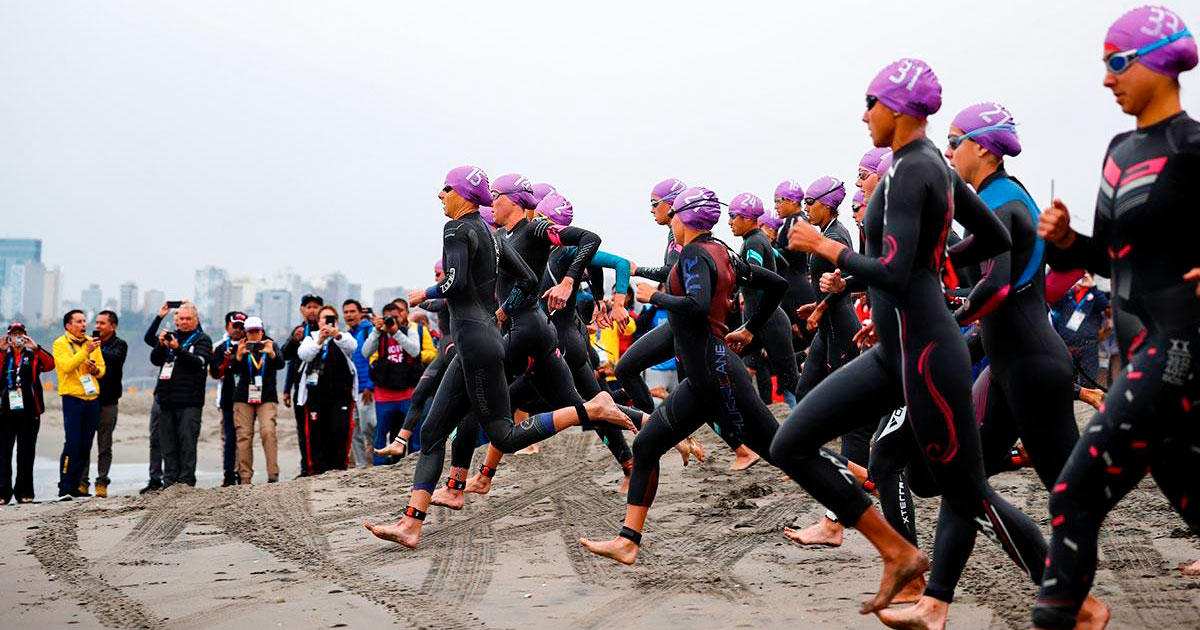 Triatletas en Lima 2019 corren hacia el mar