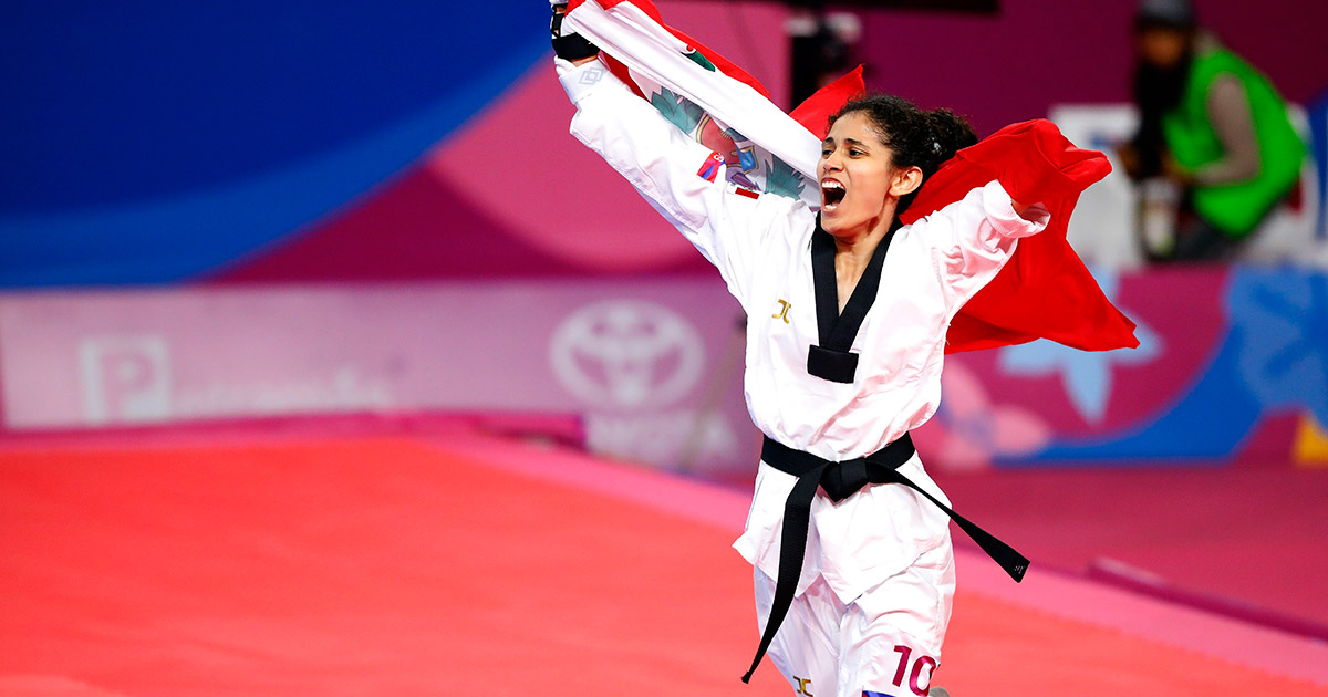 Angélica Espinoza, Peruvian Para athlete, celebrates the gold medal won in Para Taekwondo at Lima 2019 with a flag on her back.