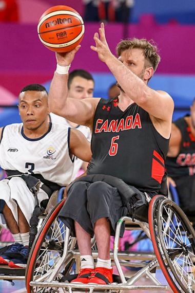 Robert Hedges de Canadá con el balón en la mano compite contra Raul Vega de Colombia en baloncesto en silla de ruedas en la Villa Deportiva Nacional – VIDENA en Lima 2019
