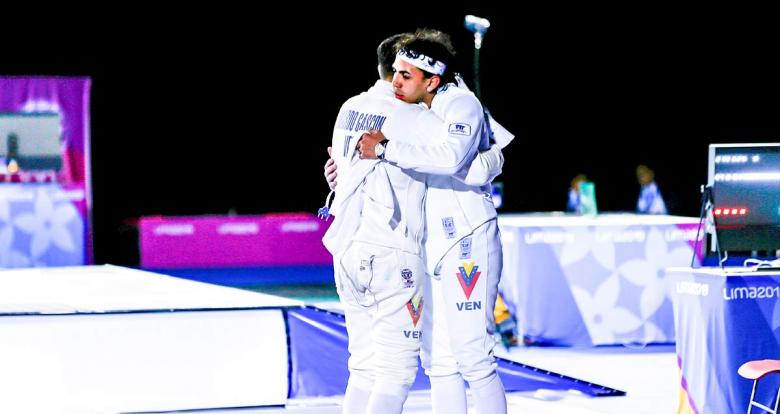 Venezuelan fencers hug at the end of the men’s individual épée final at the Lima Convention Center