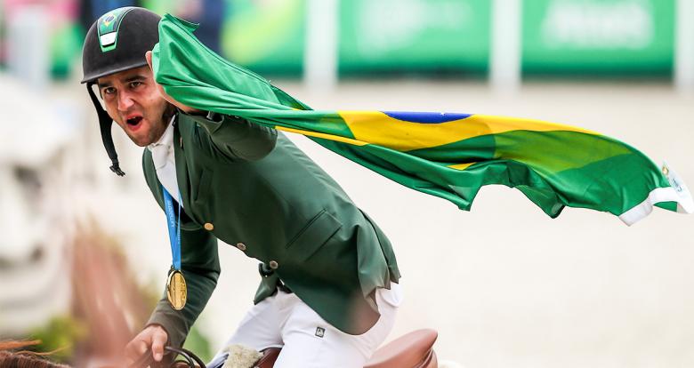 Marlon Zanotelli of Brazil celebrates gold by lifting his flag at the Army Equestrian School