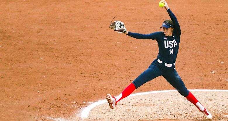 Mónica Abbott de EE. UU., tomando impulso, para lanzar con fuerza pelota de sóftbol, hacía equipo de Canadá, en Lima 2019, en Complejo Deportivo Villa María del Triunfo.