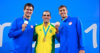 Nathan Adrian de Estados Unidos ganó la medalla de plata, Bruno Giusseppe Fratus de Brasil se llevó la de oro, y Michael Chadwick de Estados Unidos la de bronce posan sonrientes en el podio, en los Juegos Lima 2019