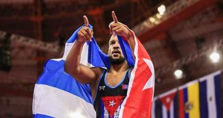 Alejandro Valdes de Cuba celebra y señala al público con la bandera cubana sobre sus hombros, tras celebra su victoria ante Albaro Rudesindo de Republica Dominicana, en los Juegos Lima 2019, en la Villa Deportiva Regional del Callao
