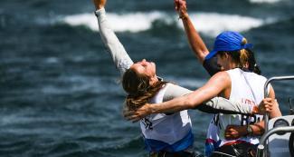Patrícia Freitas of Brazil (gold), Celia Tejerina of Argentina (silver) and María Bazo of Peru (bronze) hug to celebrate winning their medals in the Lima 2019 women’s windsurf competition at Paracas Bay.
