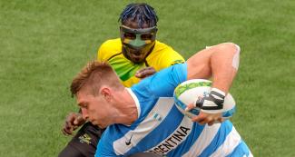 Argentinian Matias Osadczuk holds rugby ball while Jamaican Orlando Edie tries to grab it.