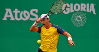 Alejandro González, tenista colombiano, golpeando pelota con raqueta de tenis en el Club Lawn Tennis