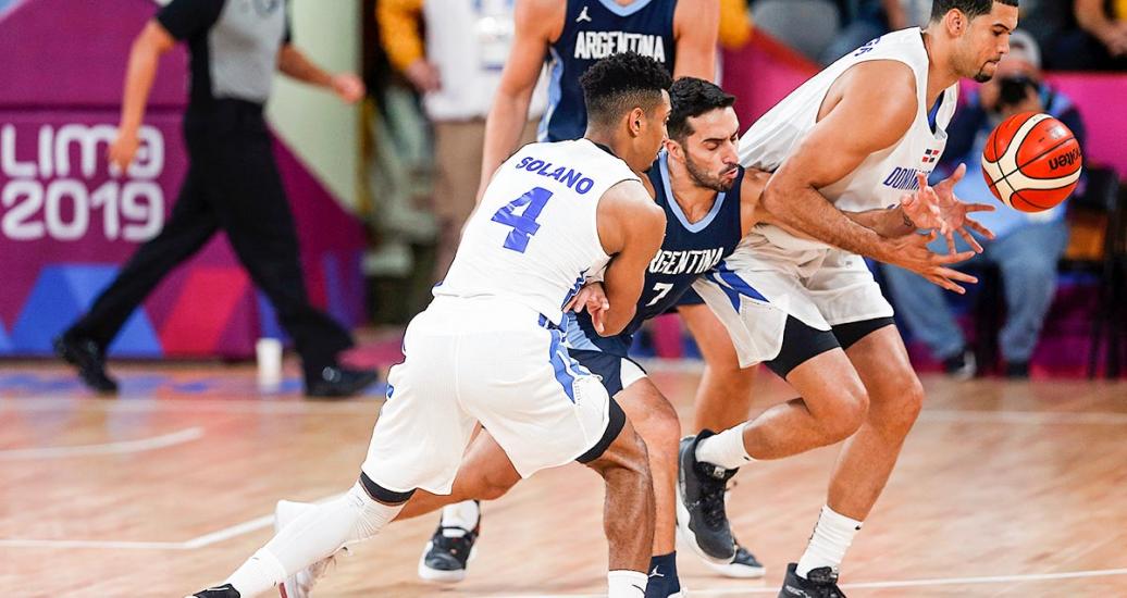 Gelvis Solano y Eloy Vargas, de República Dominicana, rodean al jugador argentino Facundo Campazzo para quitarle el balón en competencia de baloncesto de los Juegos Lima 2019, en el Coliseo Eduardo Dibós.