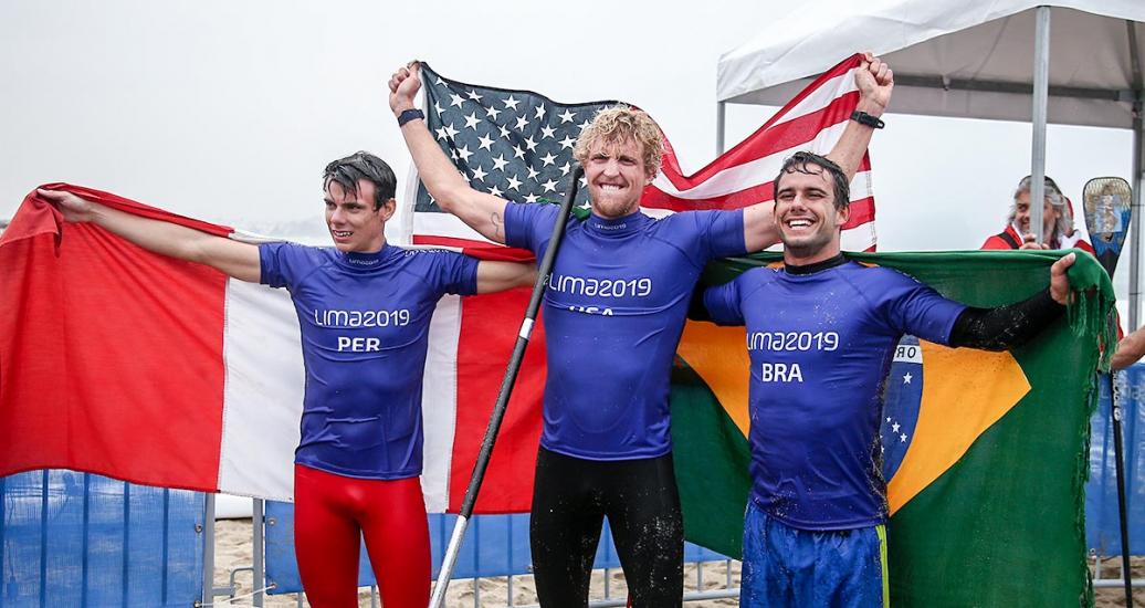 Itzel Delgado from Peru, Connor Baxter from the US and Vinicius Martins from Brazil celebrating their victory in men’s SUP surfing in Punta Rocas