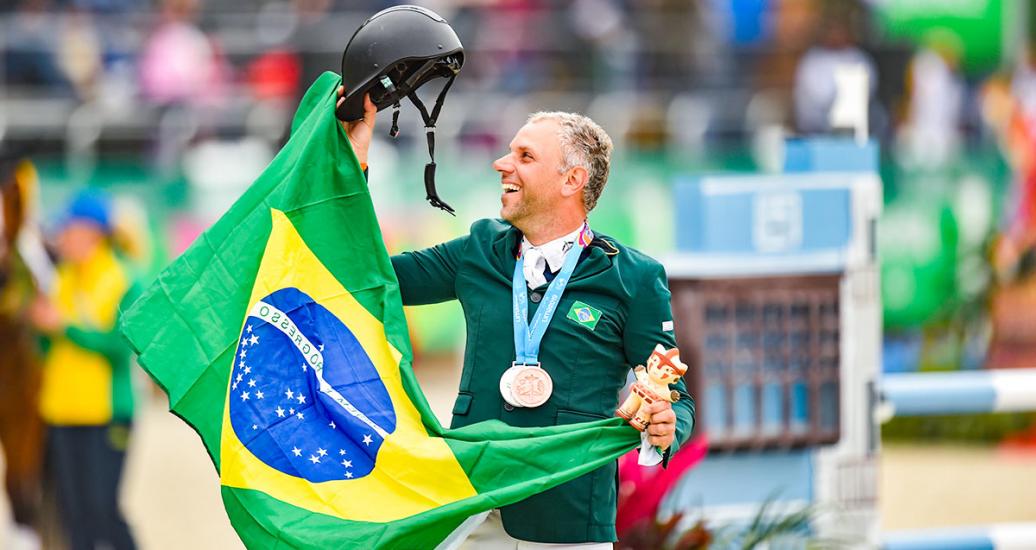 Brazilian Carlos Parro celebrates third place in Lima 2019 equestrian event with his medal and national flag at the Army Equestrian School