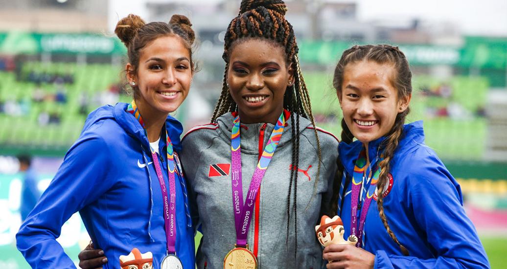 Beatriz Hatz (plata) y y Catherine Carey (bronce) de EE. UU, y Claxton Nyoshia de Trinidad y Tobago (oro) sonríen con sus medallas de Para atletismo 100 m mujeres T64 en los Juegos Parapanamericanos Lima 2019 en la Villa Deportiva Nacional – VIDENA.