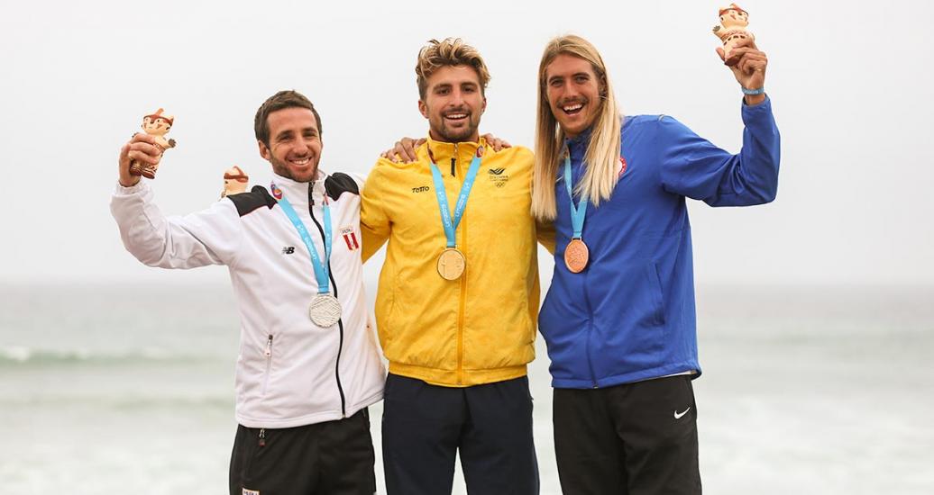 Peruvian Tamil Martino (silver), Colombian Giorgio Gomez (gold) and American Daniel Hughes (bronze) celebrate their medals at the Lima 2019 Games, in Punta Rocas