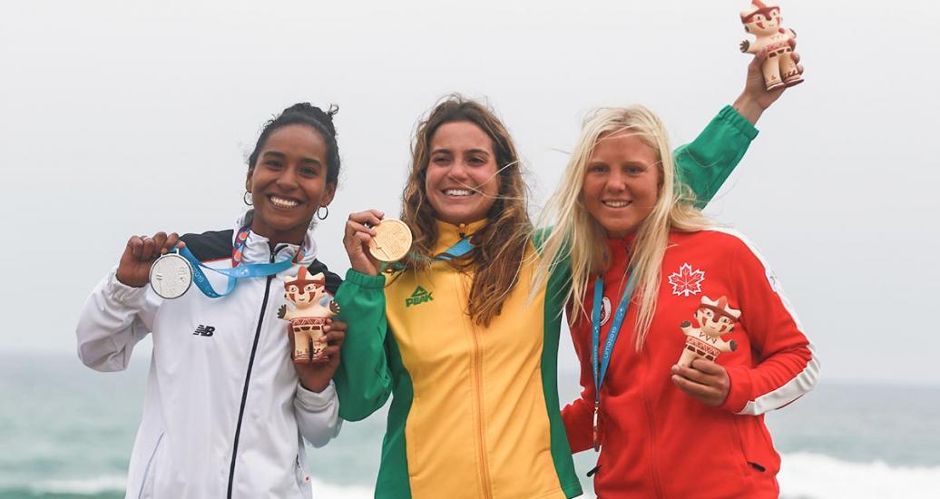 Peruvian Maria Fernandez (silver), Brazilian Chloe Calmon (gold) and Canadian Mathea Dempfle (bronze) celebrate their medals at Lima 2019 Games, in Punta Rocas